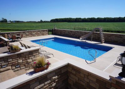 a swimming pool with a slide and a stone wall