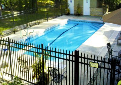 a pool with a fence and chairs